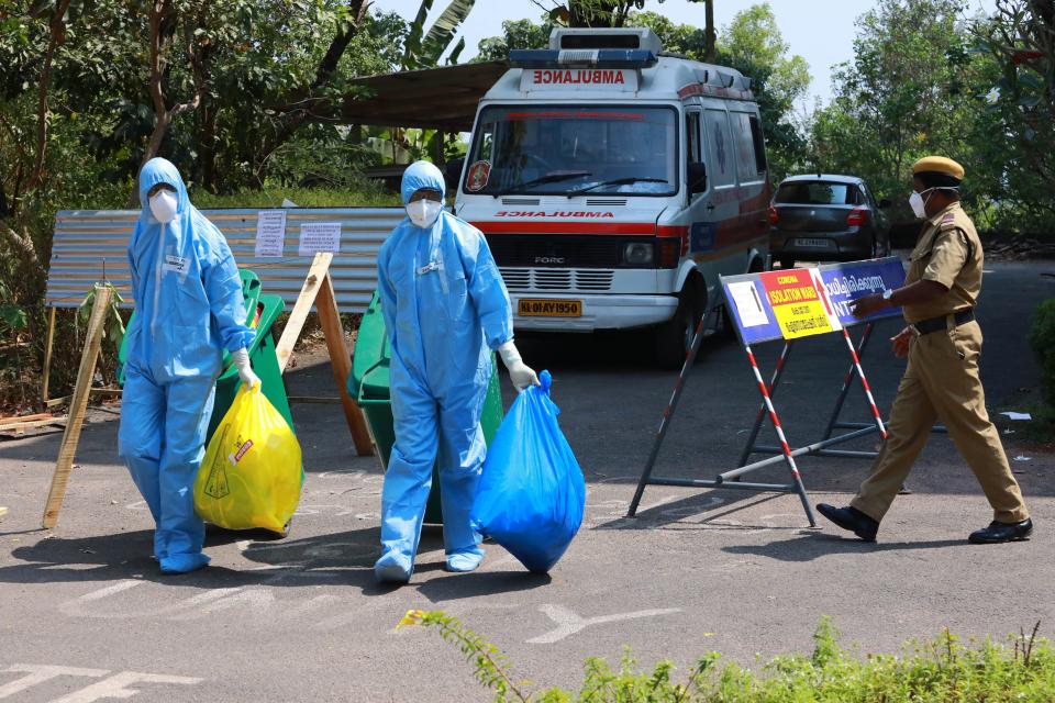 Heath officials in full protective apparel carry medical waste out of an isolation ward of Ernakulam medical in Kochi.