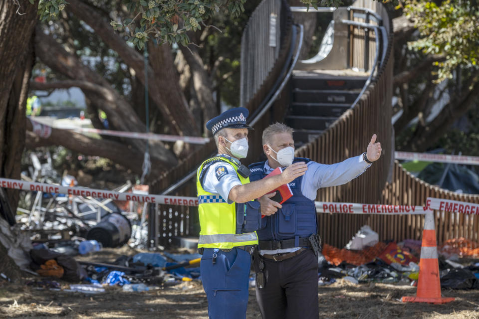 Police officers gesture as work begins to clean up the grounds outside Parliament following Wednesday's violent end to protests opposing coronavirus vaccine mandates in Wellington, New Zealand, Thursday, March 3, 2022. Since the beginning of the pandemic, New Zealand has reported fewer than 100 virus deaths among its population of 5 million, after it imposed strict border controls and lockdowns to eliminate earlier outbreaks. (Mike Scott/New Zealand Herald via AP)