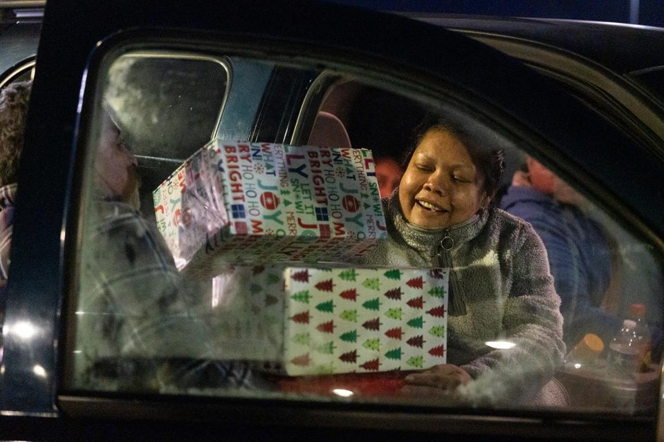 A joyful Brendy Salas juggles presents for her children from Operation Christmas Gift.