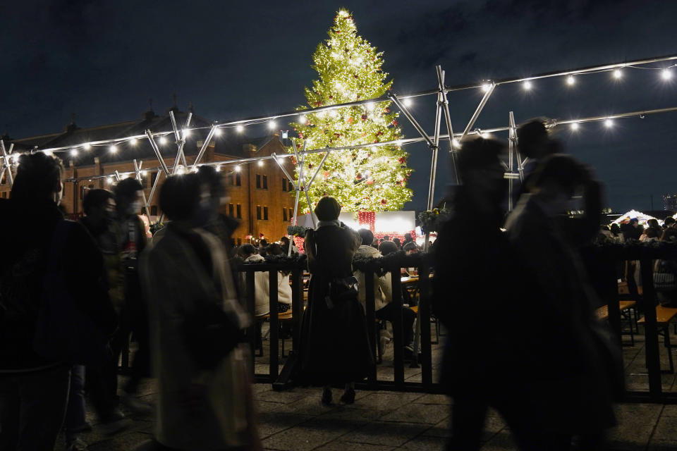 People wearing a face mask, walk past a Christmas tree, at a shopping mall in Yokohama, near Tokyo, Saturday, Dec. 25, 2021. (AP Photo/Shuji Kajiyama)