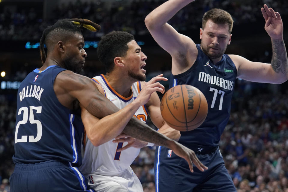 Phoenix Suns guard Devin Booker (1) is fouled by Dallas Mavericks forward Reggie Bullock (25) as guard Luka Doncic (77) looks on during the first half of Game 6 of an NBA basketball second-round playoff series Thursday, May 12, 2022, in Dallas. (AP Photo/Tony Gutierrez)