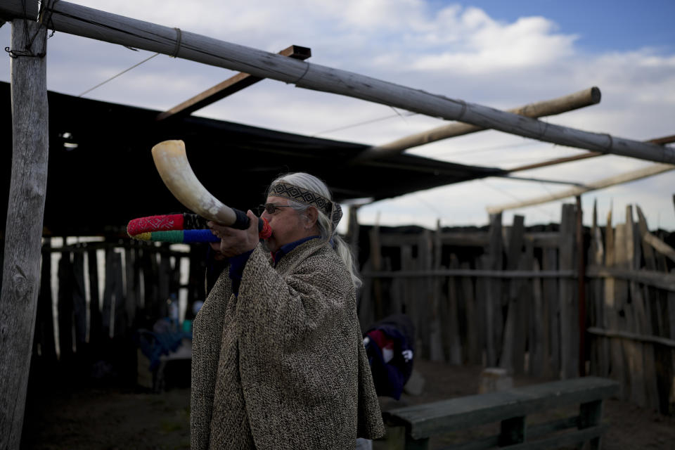 Un indígena mapuche hace sonar un cuerno en las ceremonias del día previo a la liberación de dos cóndores en Sierra Paileman (Argentina). Foto del 13 de octubre del 2022. Las dos aves, nacidas en cautiverio, fueron soltadas al día siguiente. (AP Photo/Natacha Pisarenko)