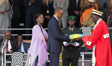 Rwanda's newly inaugurated President Paul Kagame (C) receives the National flag from Chief Justice Sam Rugege next to First Lady Jeannette Kagame after taking the oath of office during his swearing-in ceremony at Amahoro stadium in Kigali, Rwanda, August 18, 2017. REUTERS/Jean Bizimana