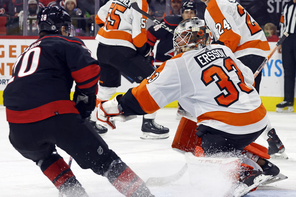 Philadelphia Flyers goaltender Samuel Ersson (33) gloves the puck in front of Carolina Hurricanes' Sebastian Aho (20) during the second period of an NHL hockey game in Raleigh, N.C., Friday, Dec. 23, 2022. (AP Photo/Karl B DeBlaker)