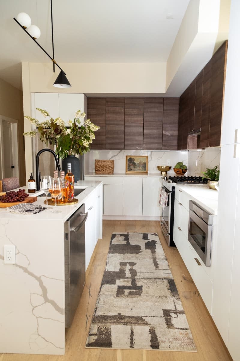 A kitchen with a white cabinet base, stainless steel appliances, and wooden upper cabinets.