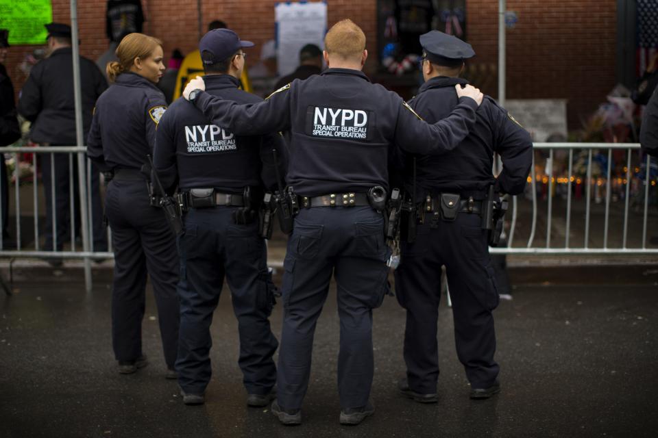 New York City Police officers pause as they visit a makeshift memorial at the site where two of their fellow police officers were fatally shot in the Brooklyn borough of New York, December 23, 2014. NYPD officers, Wenjian Liu and Rafael Ramos were shot and killed as they sat in a marked squad car in Brooklyn on Saturday afternoon, New York Police Commissioner William Bratton said. The suspect in the shooting then shot and killed himself, according to Bratton. REUTERS/Mike Segar (UNITED STATES Tags: - Tags: SOCIETY CIVIL UNREST TPX IMAGES OF THE DAY)