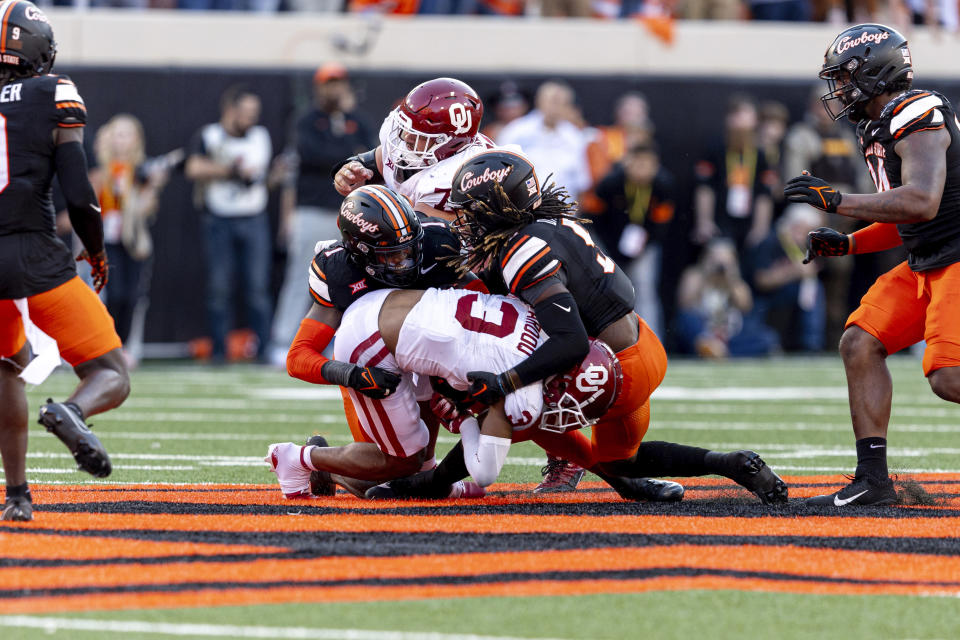 Oklahoma State linebacker Xavier Benson (1) and safety Kendal Daniels (5) tackle Oklahoma wide receiver Jalil Farooq (3) in the second half of an NCAA college football game Saturday, Nov. 4, 2023, in Stillwater, Okla. (AP Photo/Mitch Alcala)