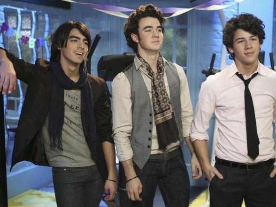 Joe, Kevin, and Nick Jonas smiling in verts and ties.