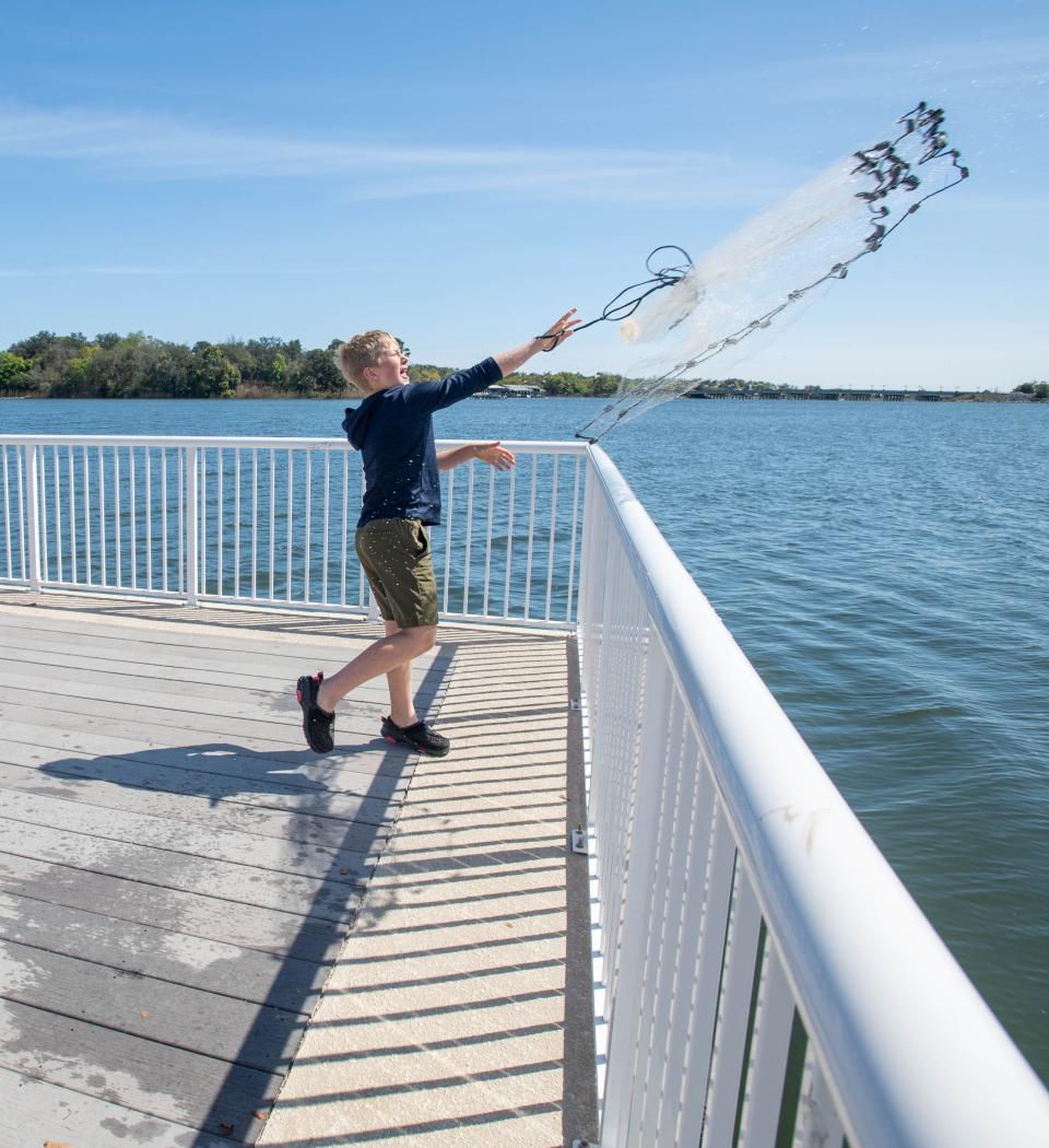 Tobias Hunter, 9, of Lafayette, Louisiana, casts a net while fishing from a dock along Bayou Texar in Pensacola on Tuesday, March 14, 2023.