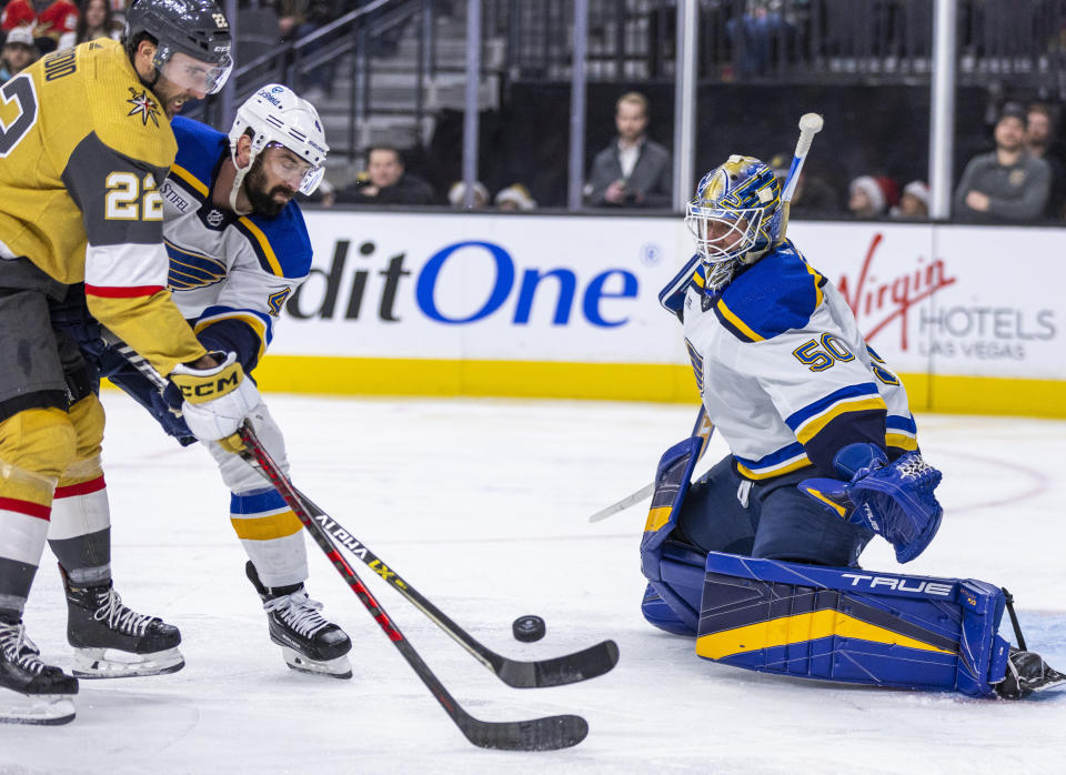 Vegas Golden Knights center Michael Amadio (22), defended by St. Louis Blues' Nick Leddy (4), tries to shoot on goaltender Jordan Binnington (50) during the second period of an NHL hockey game Friday, Dec. 23, 2022, in Las Vegas. (AP Photo/L.E. Baskow)