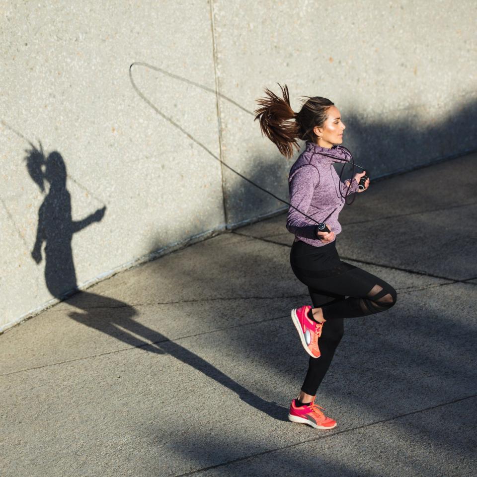 Fitness woman skipping with a jump rope outdoors