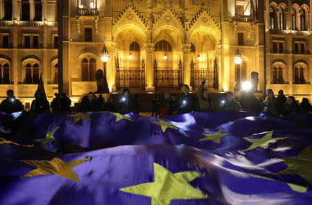 People hold a big European Union flag during a protest against a proposed new labor law, billed as the "slave law", in front of the Parliament building in Budapest, Hungary, December 18, 2018. REUTERS/Marko Djurica