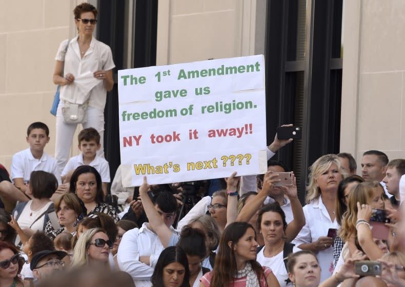 FILE - In this Aug. 14, 2019, file photo, people wait in line to hear attorneys speak at a hearing challenging the constitutionality of the state legislature's repeal of the religious exemption to vaccination outside the Albany County Courthouse in Albany, N.Y. New York's revocation of a longtime religious exemption for vaccinations has parents scrambling to either get kids shots, or get them out of the classroom as the school year begins. Lawmakers did away with the religious exemption in June amid the nation's worst measles outbreak since 1992. (AP Photo/Hans Pennink, File)