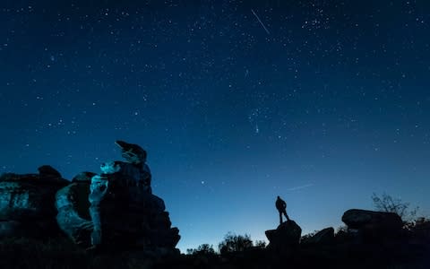 A plane and a satellite passing by a man stargazing at Brimham Rocks in Yorkshire as the Orionid meteor shower reached its peak - Credit: Danny Lawson/PA