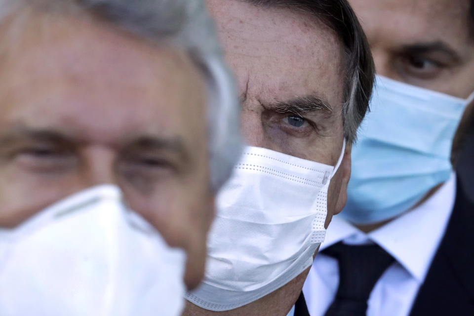 FILE - In this March 24, 2021 file photo, Brazilian President Jair Bolsonaro, center, arrives for a press conference following a meeting about the federal government's response to the COVID-19 pandemic at the presidential residence Alvorada Palace in Brasilia, Brazil. Tightened public health measures remain anathema to Bolsonaro; he has called lockdown measures "absurd". (AP Photo/Eraldo Peres, File)