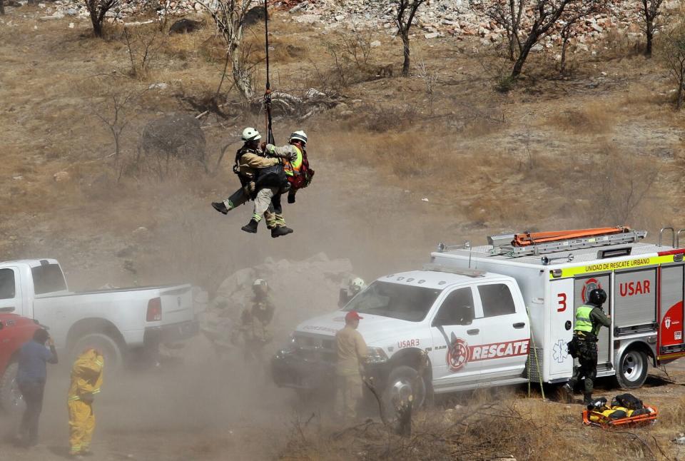 Forensic experts work with several bags of human remains extracted from the bottom of a ravine