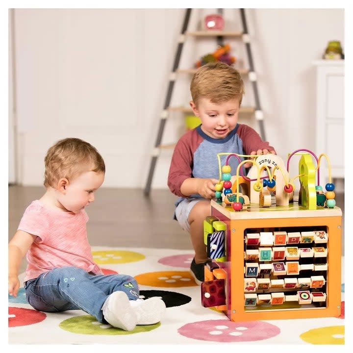 Two child models playing with wooden cube with various fun functions