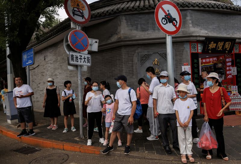 FILE PHOTO: People wear face masks as they stand in a street following a coronavirus disease (COVID-19) outbreak, in Beijing