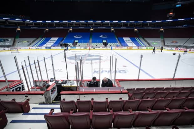 Off-ice officials pack up equipment after the Vancouver Canucks and Calgary Flames NHL hockey game was postponed due to a positive COVID-19 test result in Vancouver on Wednesday, March 31, 2021.