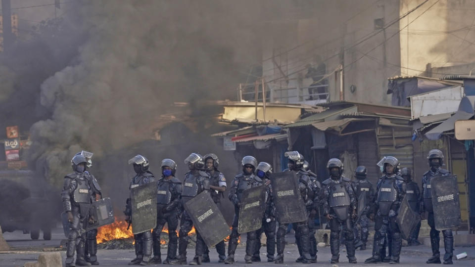 Gendarmes with smoke rising behind them in Dakar, Senegal - 9 February 2024