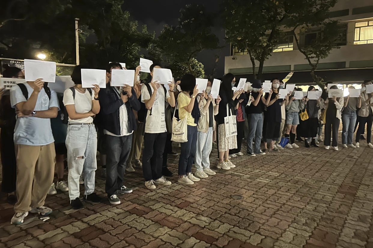 Protesters in Hong Kong hold up blank white papers during a commemoration for victims of the Urumqi fire. 
