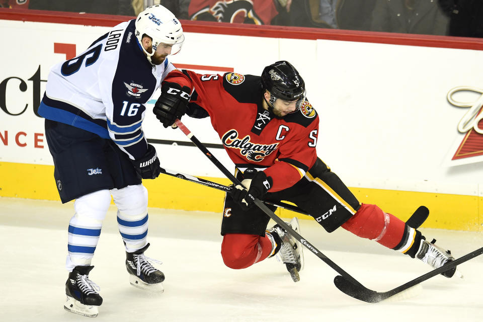 Feb 2, 2015; Calgary, Alberta, CAN; Calgary Flames defenseman Mark Giordano (5) battles for the puck with Winnipeg Jets left wing Andrew Ladd (16) during the second period at Scotiabank Saddledome. (Candice Ward-USA TODAY Sports)