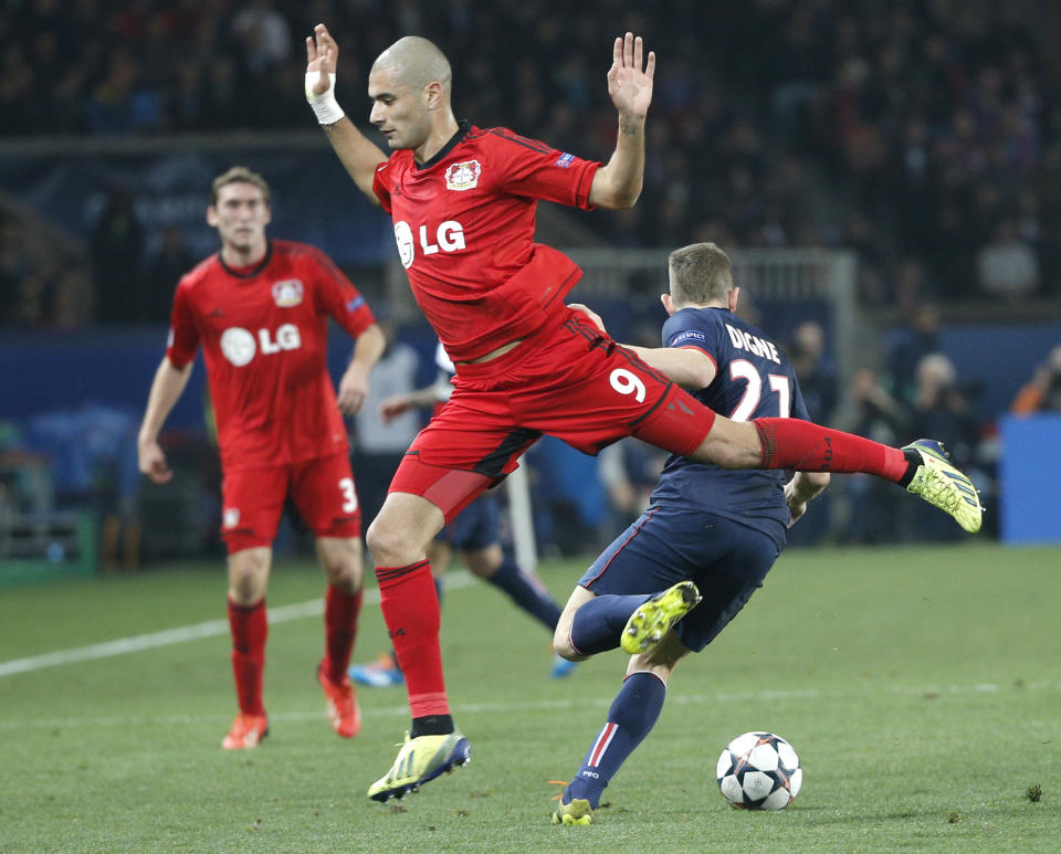 Leverkusen's Eren Derdiyok, front, jumps while PSG's Lucas Digne runs with ball during the Champions League round of 16 second leg soccer match between Paris Saint Germain and Bayer Leverkusen at the Parc des Princes stadium in Paris, Wednesday, March 12, 2014. (AP Photo/Christophe Ena)