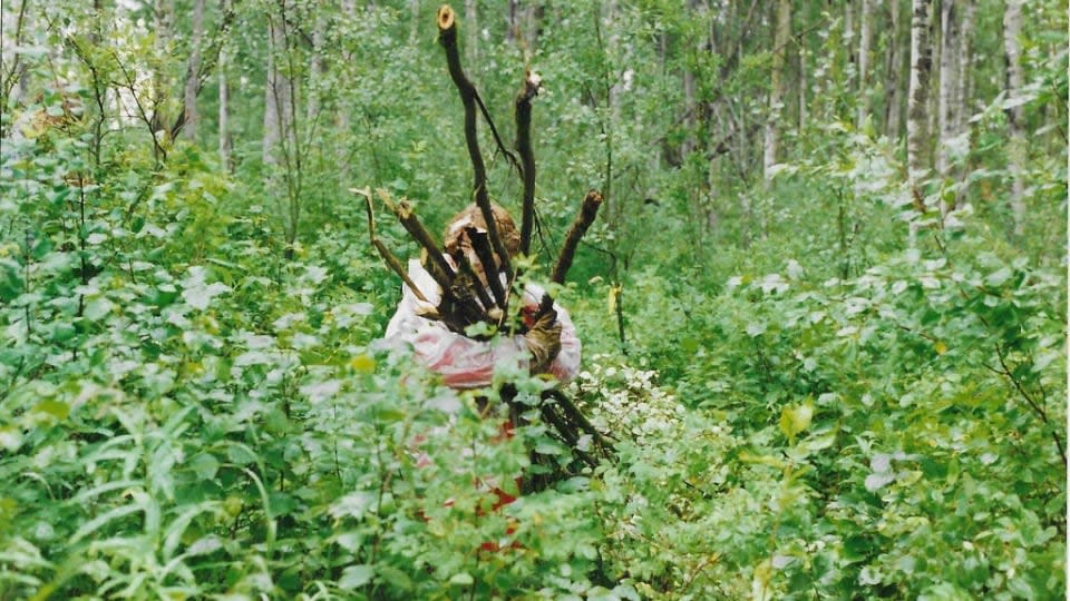 After years of neglect, the cemetery began overgrown with. In this photograph from 1997, a volunteer carries away a bundle of tree branches as work begins to restore the site. 