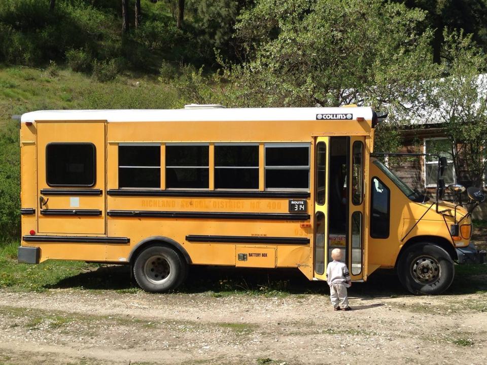 a yellow school bus parked in front of a green wooded area