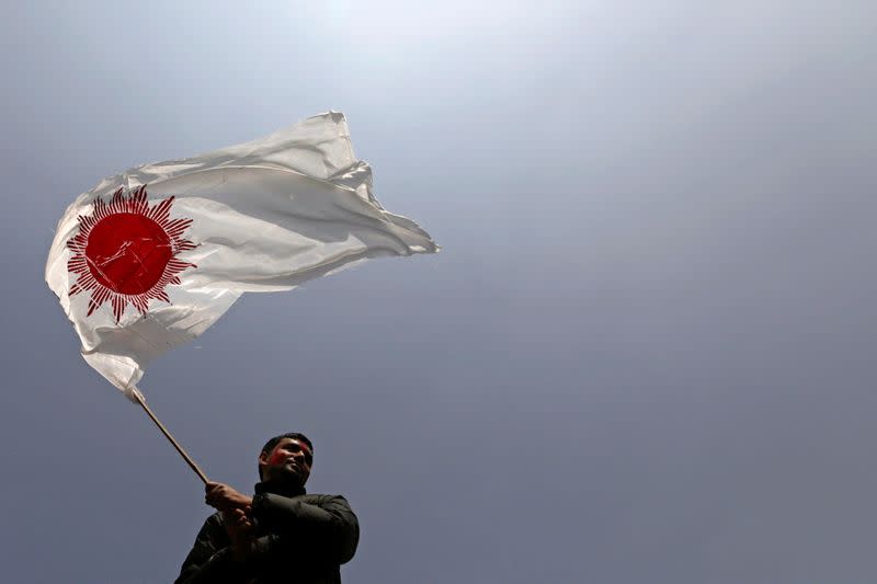 A supporter of a faction of the ruling Nepal Communist Party holds a party flag as he takes part in a rally celebrating the reinstatement of the parliament by Nepal’s top court in Kathmandu