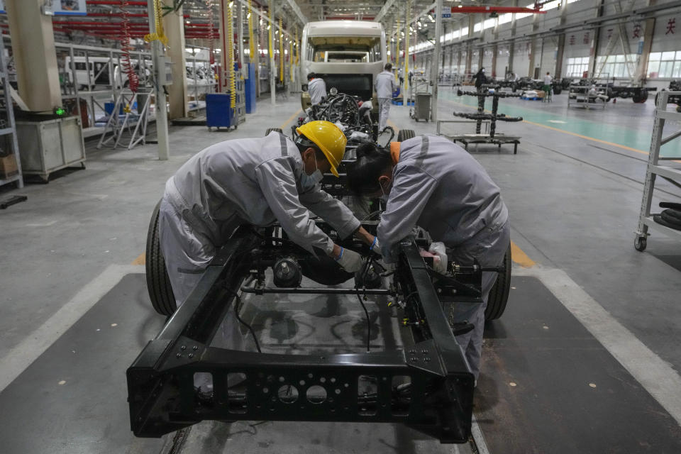 Workers assemble a chassis frame of a minibus at a Tenglong Automobile Co. manufacturing factory during a media-organized tour in Xiangyang in central China's Hubei Province on May 10, 2023. China's manufacturing and consumer spending are weakening after a strong start to 2023 after anti-virus controls ended. (AP Photo/Andy Wong)