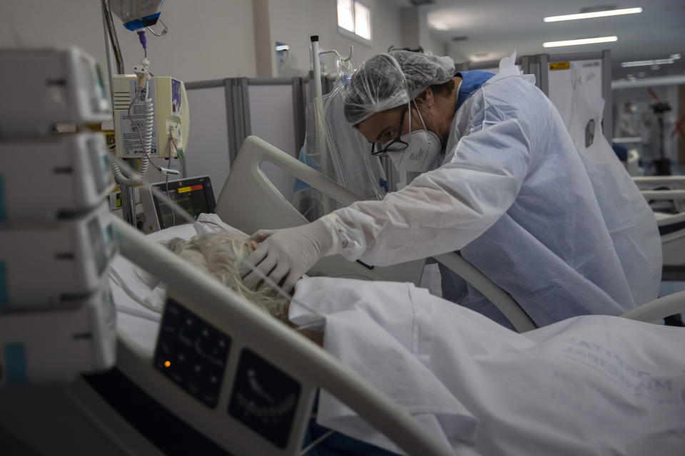 A health worker treats a COVID-19 patient at the intensive care unit of the Dr. Ernesto Che Guevara hospital in Marica, Brazil, Wednesday, Jan. 26, 2022. (AP Photo/Bruna Prado)