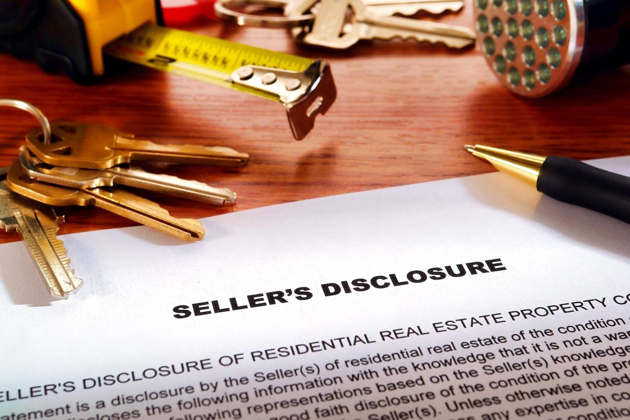 real estate homeowner seller property disclosure condition statement with house keys and inspection flashlight on a home owner desk