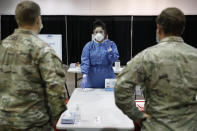 Diana Vega, a registered respiratory therapist, instructs Nevada National Guardsman on how to test people during the setup of a temporary coronavirus testing site Monday, Aug. 3, 2020, in Las Vegas. (AP Photo/John Locher)