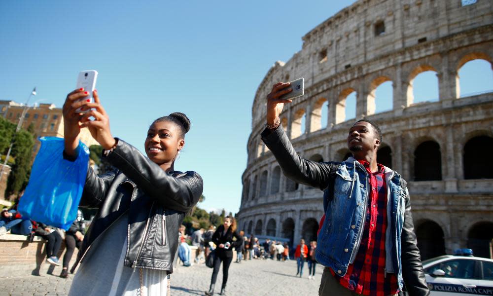 Tourists take a selfie in front of the Colosseum in Rome.