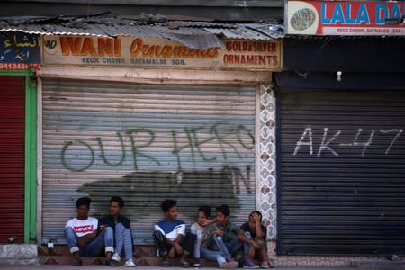 Kashmir boys sit in front of closed shops during restrictions in Srinagar