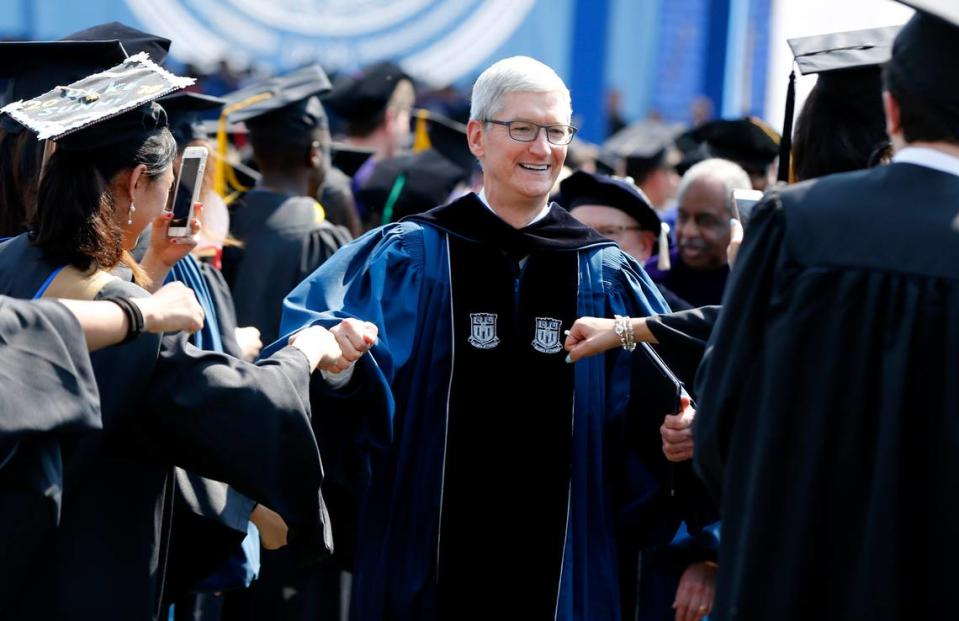 Apple CEO Tim Cook fist bumps graduates while leaving Duke University’s commencement on Monday. His company is considering locating some of its operations in the Triangle.