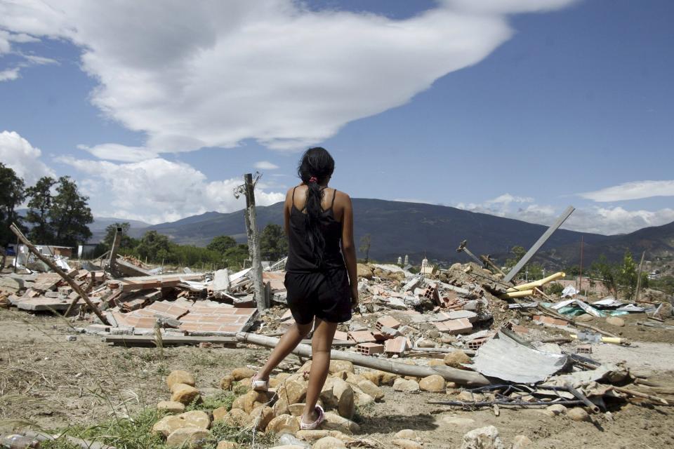 A woman stands in front of the ruins of houses of people who do not possess proper documentation to live in Venezuela in Tachira state