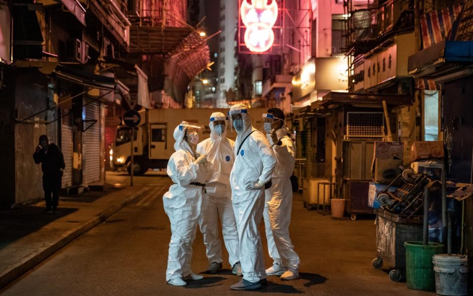 Government workers wearing personal protective equipment on a street in the locked-down part of the Jordon district on January 24, 2021 in Hong Kong, China. Hong Kong government locked-down tens of thousand of residents to contain a worsening outbreak of the coronavirus. Residents tested negative for Covid-19 can now leave and re-enter the area and the restriction is expected to lift by midnight. -  Anthony Kwan / Getty