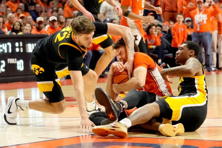 Iowa’s Owen Freeman (32) battles Illinois’ Coleman Hawkins for the ball as Tony Perkins watches during the second half of an NCAA college basketball game Saturday, Feb. 24, 2024, in Champaign, Ill. Illinois won 95-85. (AP Photo/Charles Rex Arbogast)
