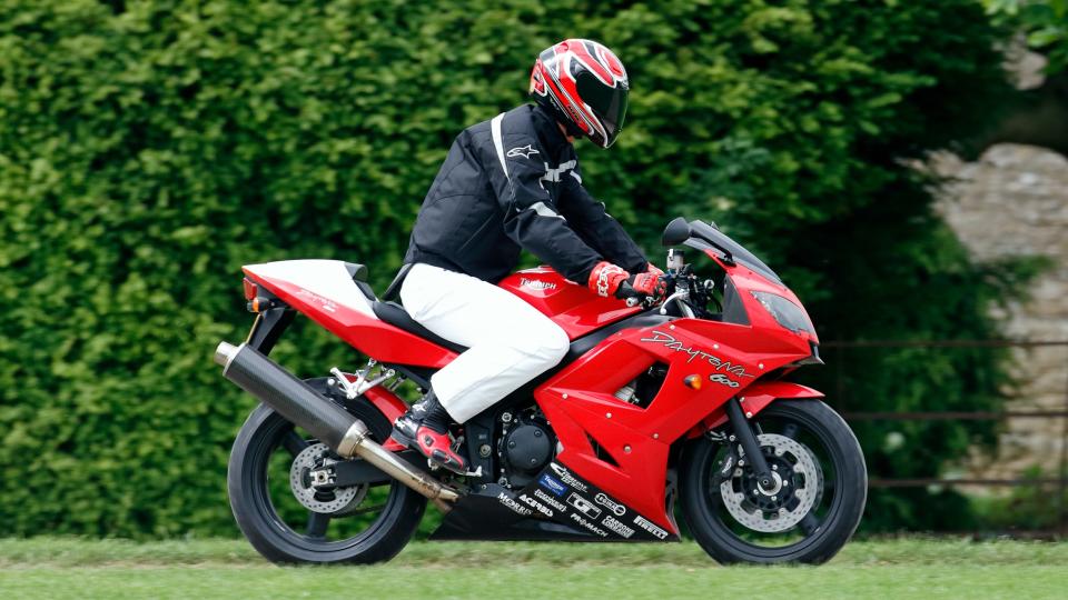 Prince William arrives, riding his Triumph Daytona 600 motorbike, to play in the Burberry Cup polo match