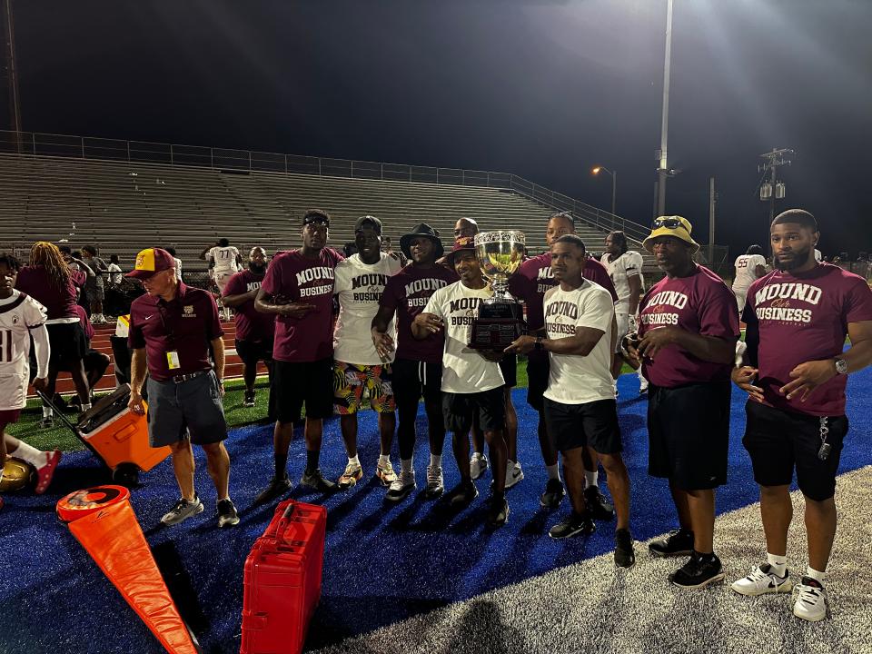 Melrose football coaches Gerald and Jarrett Morrow pose with the Soul Bowl trophy after coaching their team to a 20-7 victory over Memphis East.