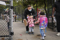 Students greet Eddie Polanco, an elementary school guidance counselor, as they arrive for in-person classes outside Public School 188 The Island School, Tuesday, Sept. 29, 2020, in the Manhattan borough of New York. Hundreds of thousands of elementary school students are heading back to classrooms starting Tuesday as New York City enters a high-stakes phase of resuming in-person learning during the coronavirus pandemic. (AP Photo/John Minchillo)