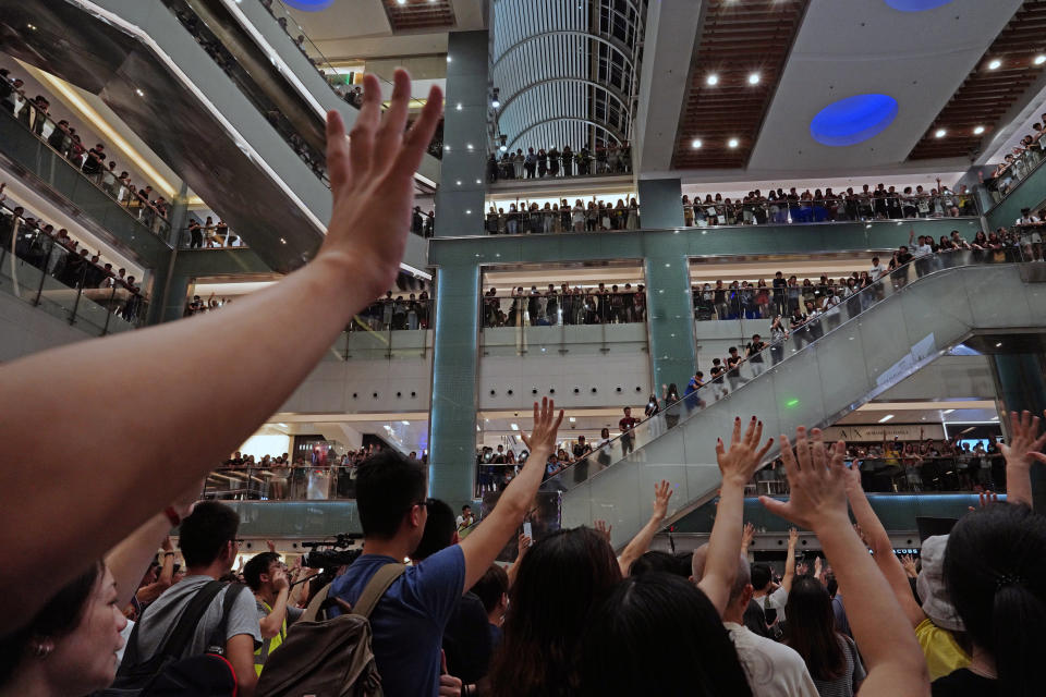 Protesters gesture as they sing a theme song written by protesters "Glory be to thee" at a shopping mall in Hong Kong Wednesday, Sept. 11, 2019. Hundreds of Hong Kong citizens gathered at several malls late Wednesday, chanting slogans and belting out a new protest song. The song, "glory to Hong Kong", was penned online and has been embraced by protesters as their anthem song. The peaceful mall gatherings marked a respite after violent clashes over the weekend. (AP Photo/Vincent Yu)