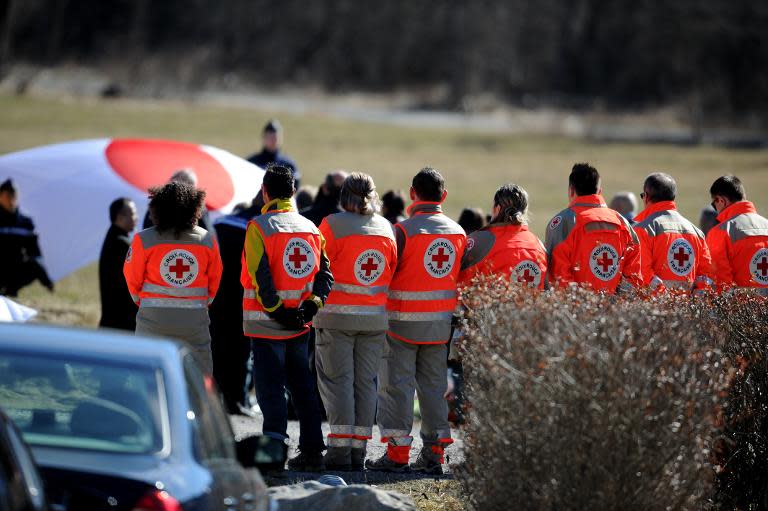 Rescuers stand as relatives of Japanese victims pay their respects to crash victims, on March 29, 2015 near a commemorative headstone in Seyne-les-Alpes