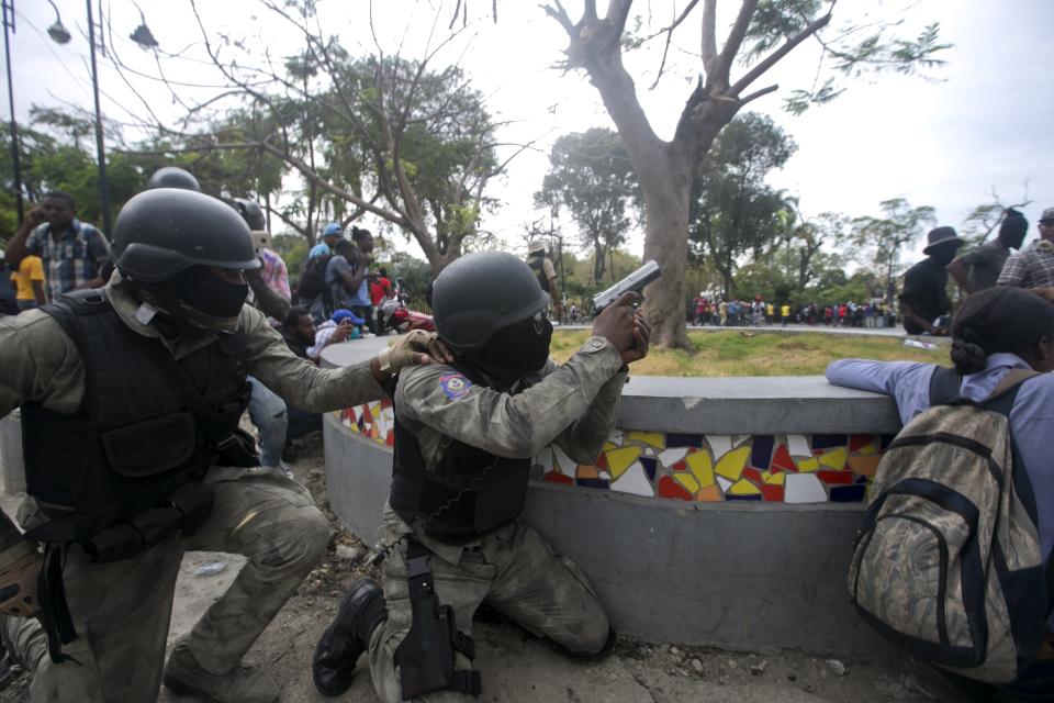 Police officers fire their weapons at army soldiers during a protest over police pay and working conditions for the national police, in Port-au-Prince, Haiti, Sunday, Feb. 23, 2020. Off-duty police officers and their supporters exchanged fire for nearly two hours with members of the newly reconstituted Haitian army in front of the national palace. (AP Photo/Dieu Nalio Chery)