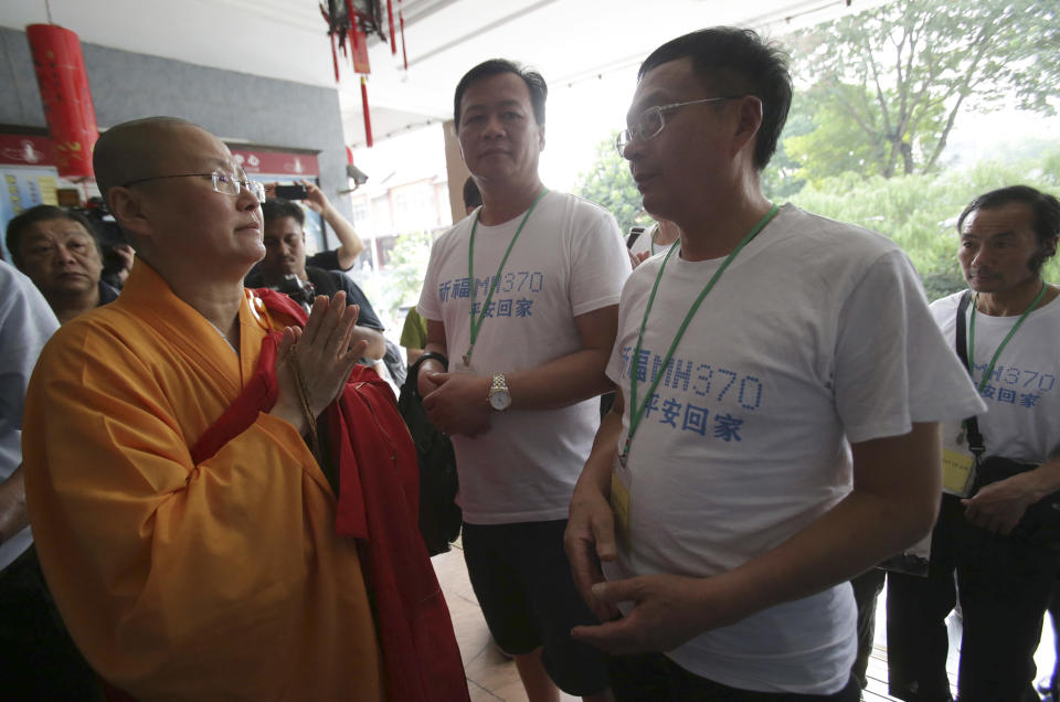 A Buddhist monk welcomes Chinese relatives of passengers on board the missing Malaysia Airlines Flight 370 as they arrive to pray at a Buddhist temple in Petaling Jaya, Malaysia, Monday, March 31, 2014. Relatives from China are in the country to seek answers as to what happened to their loved ones on board the Malaysian jet that vanished more than three weeks ago. The writing on the shirt reads "Praying that MH370 returns home safely." (AP Photo/Aaron Favila)