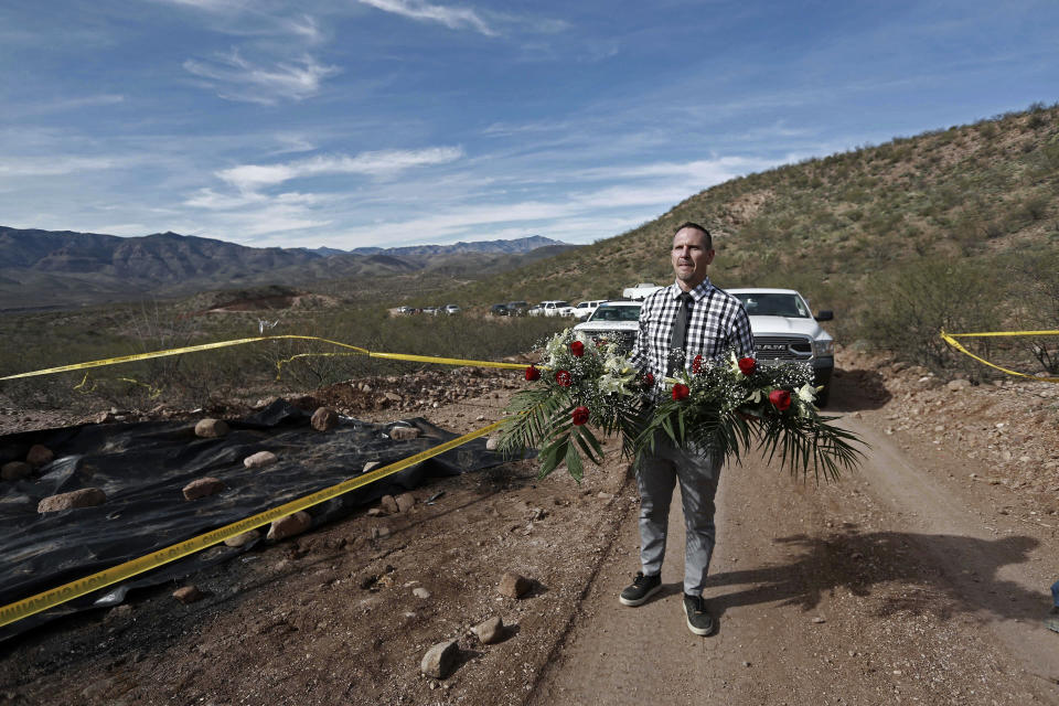 Bryan Lebaron, places flowers where one of the cars belonging to the extended LeBaron family was ambushed by gunmen last year near Bavispe, Sonora state, Mexico, Sunday Jan. 12, 2020. Lopez Obrador said Sunday there is an agreement to establish a monument will be put up to memorialize nine U.S.-Mexican dual citizens ambushed and slain last year by drug gang assassins along a remote road near New Mexico. (AP Photo/Christian Chavez)