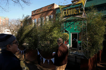 People walk on the sidewalk past the Comet Ping Pong pizza restaurant in Washington, U.S. December 5, 2016. REUTERS/Jonathan Ernst