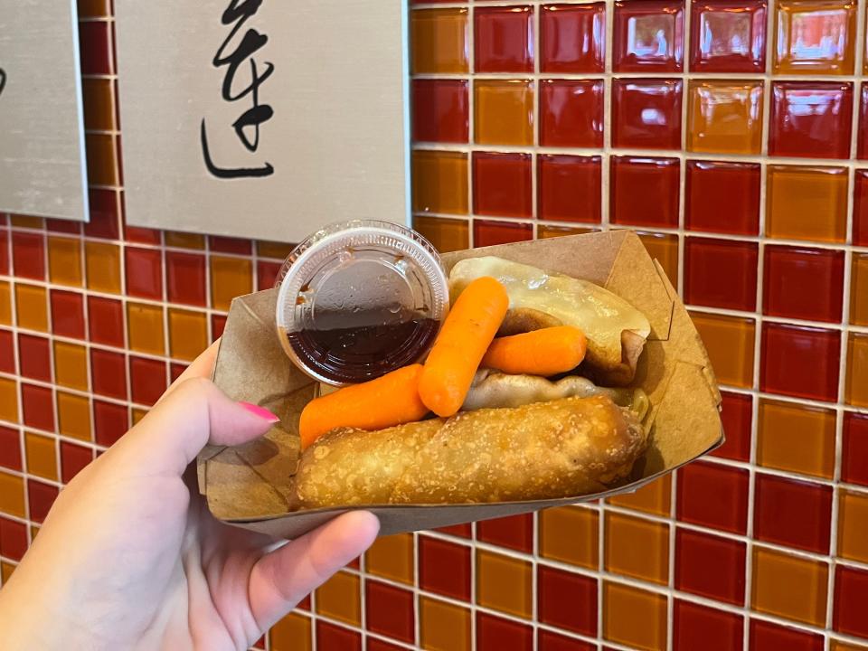 hand holding potstickers and egg roll kids' meal from epcot